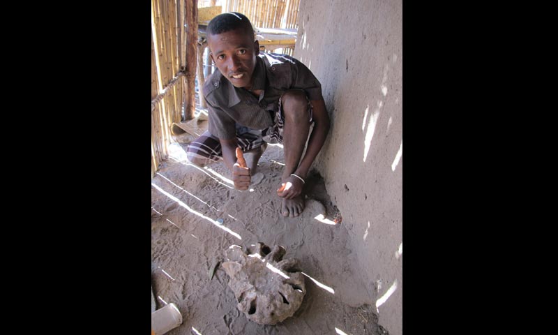 Image of A local guide with a 100-million-year-old fossil ammonite, found alongside dinosaur bones  indicating that the rocks were deposited just offshore